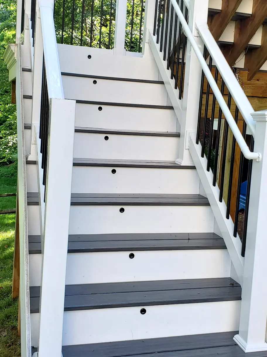 After: The same composite stairs after cleaning, with bright white risers and rails and clean gray treads